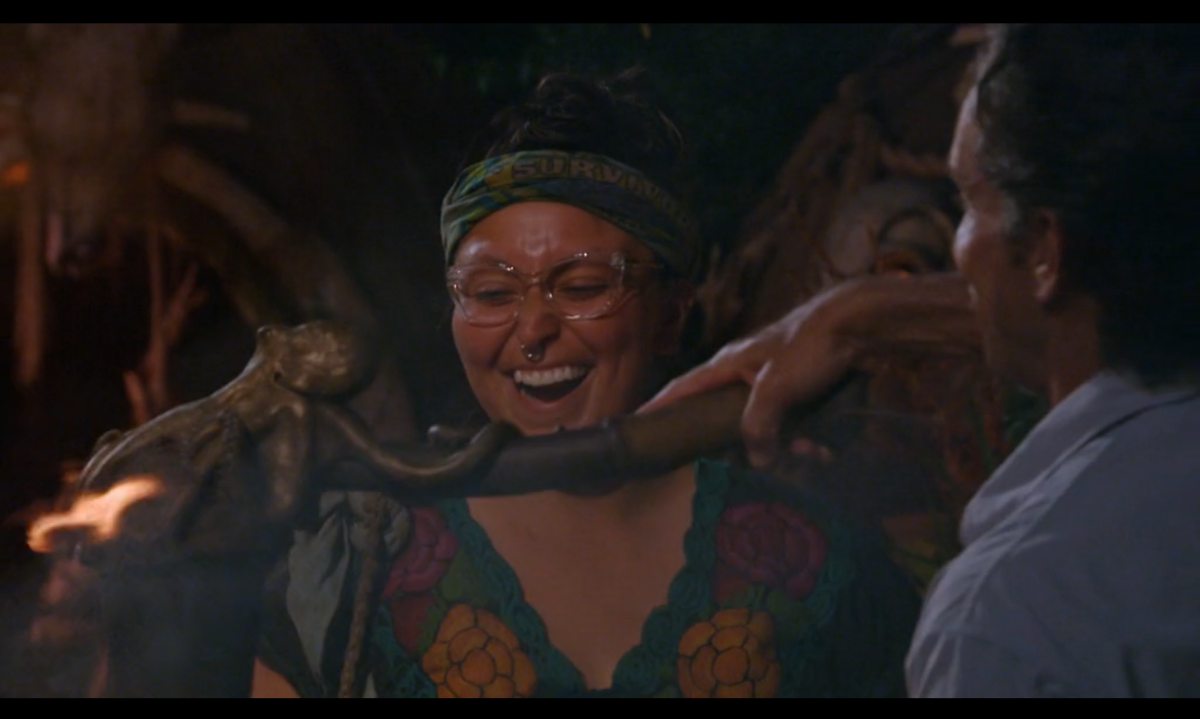 Karla Cruz Godoy, a contestant on Survivor, grinning as host Jeff Probst snuffs her torch, signaling the end of her run on the show