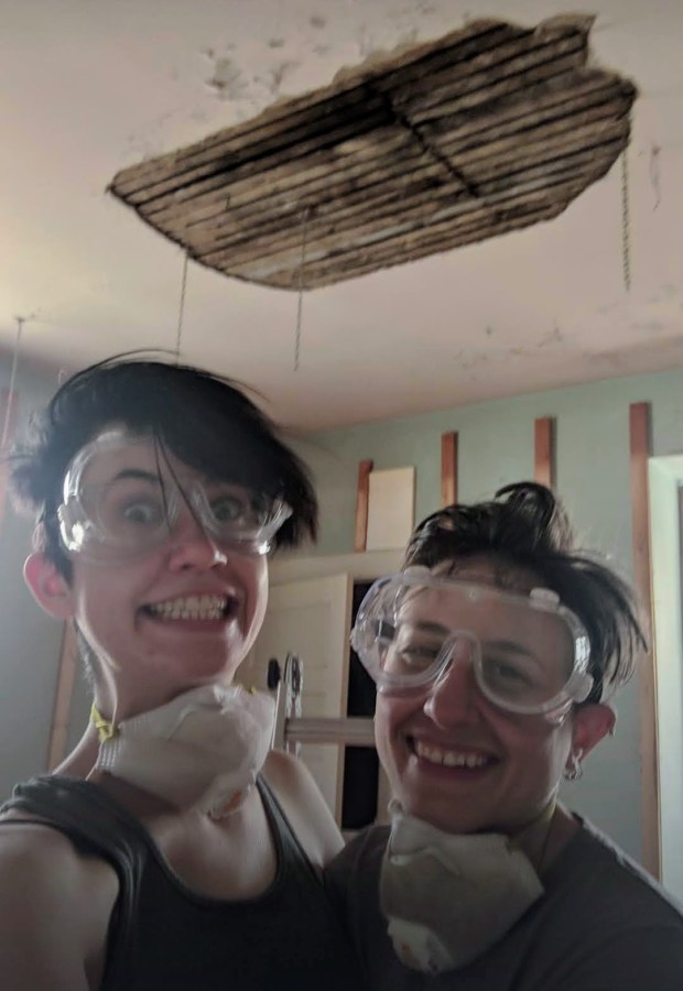 Nico and Sadie engaged in home reno beneath a crumbling plaster ceiling, making funny faces