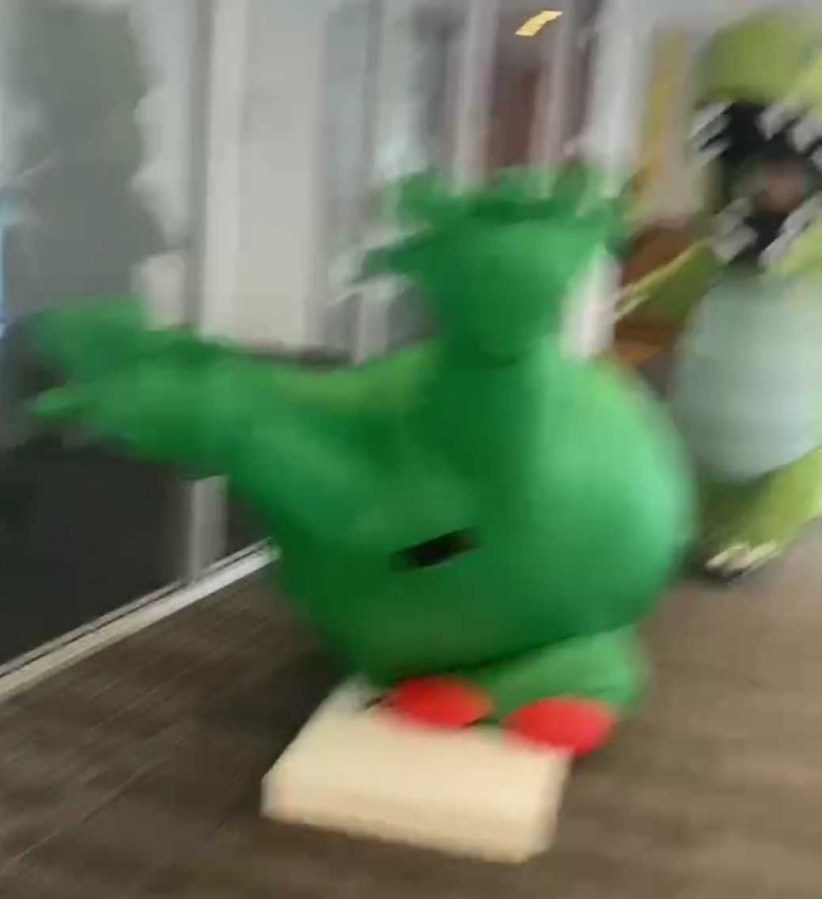 a blurry photo of Julie wearing a frog costume on halloween and falling over a corn hole board, titled "halloween frog disaster"