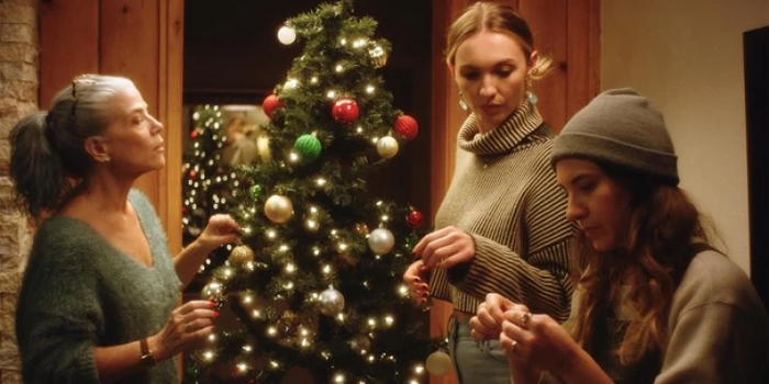 Two white women and one of their mothers decorating a Christmas tree