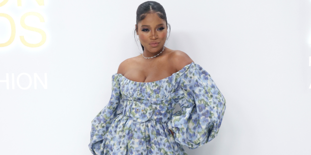 KeKe Palmer wears a blue and white floral dress on a red carpet.