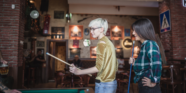 Two women play billiards in a bar