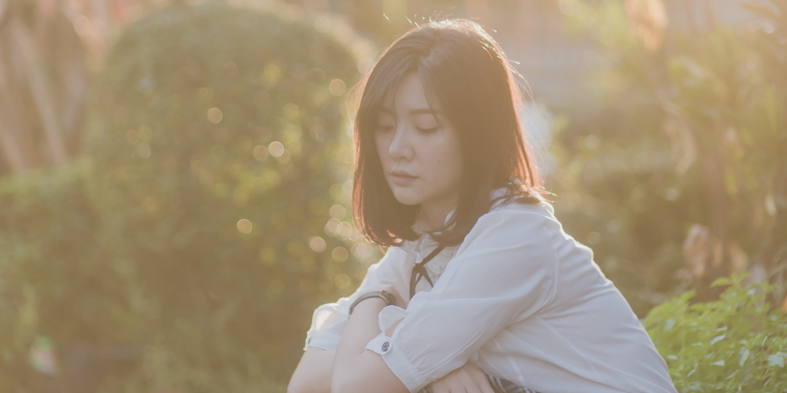 lonely woman sits alone outside, thinking of someone who isn't there