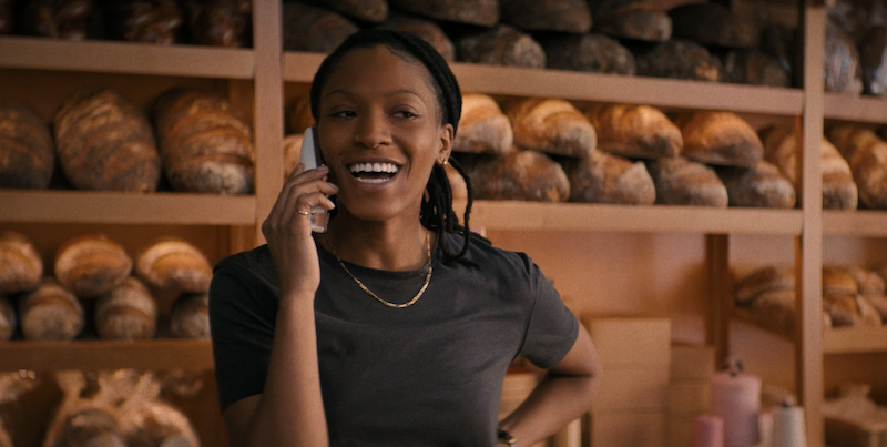 Terri smiling while talking on the phone and standing in front of many loaves of bread