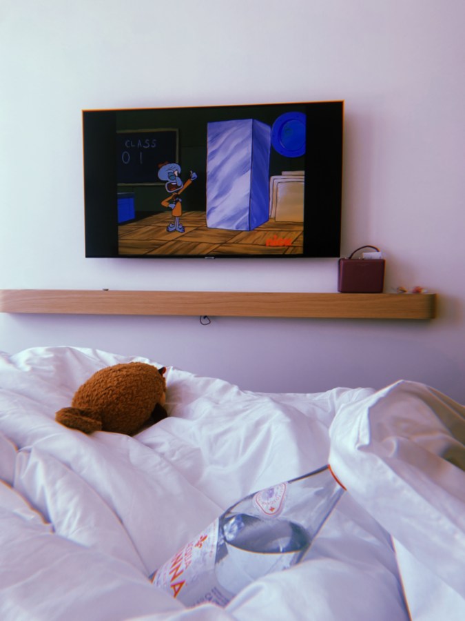 Hotel bed ruffled up with Spongebob on the TV