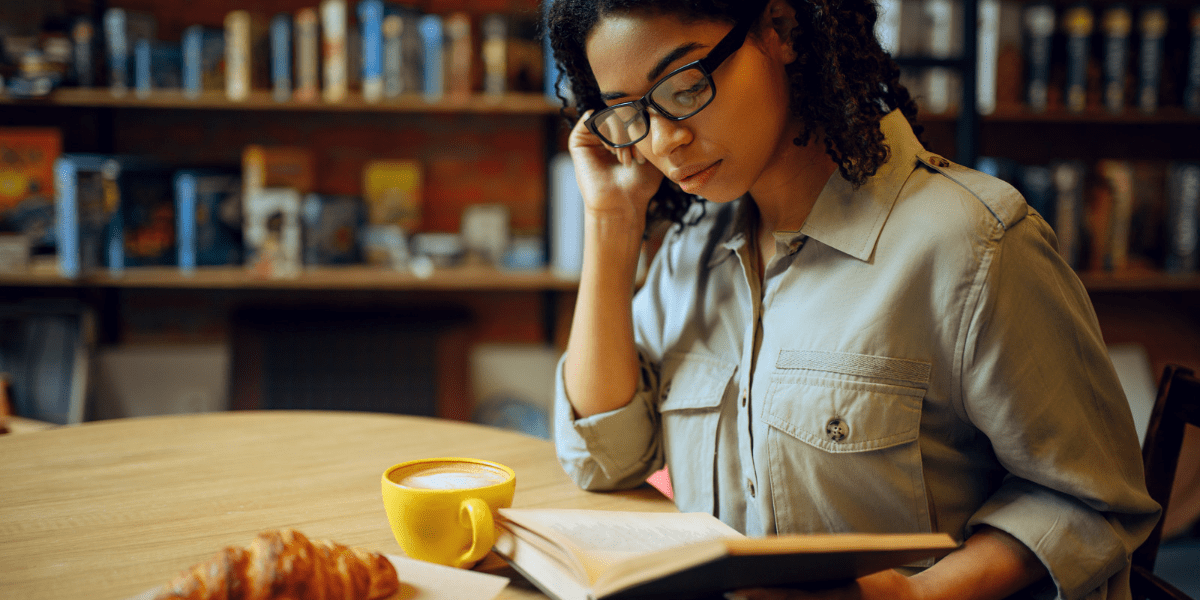 Black Woman at a coffee shop reading a book