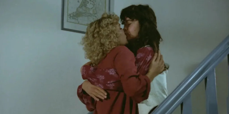 Two women kiss on a staircase.