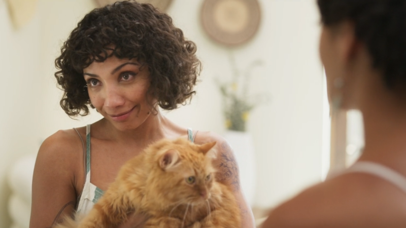 Fantasy Island: Jasika Nicole's character smiles while holding a fluffy orange cat