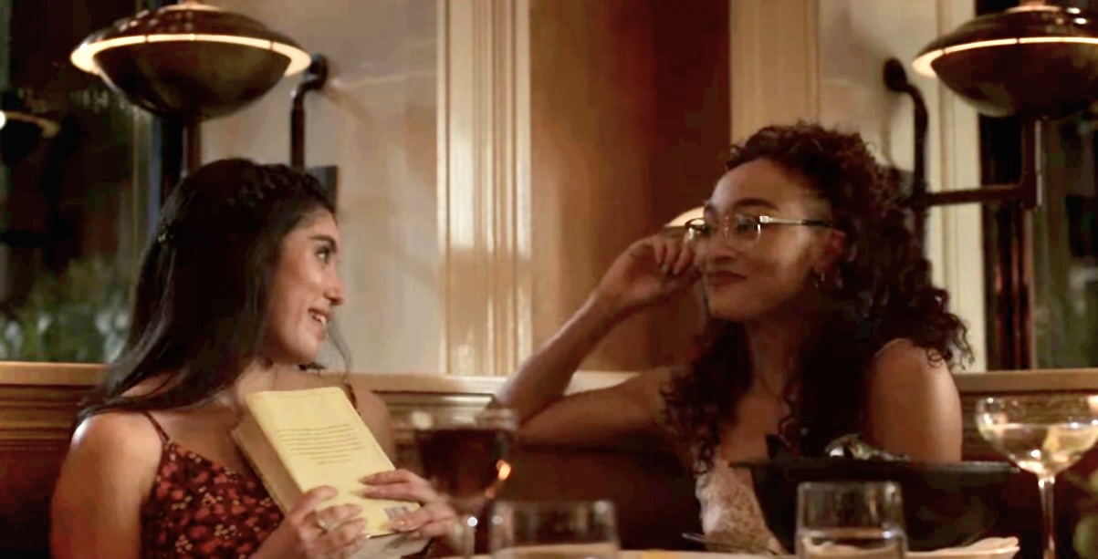 two girls sitting in a restaurant gazing at each other gayly