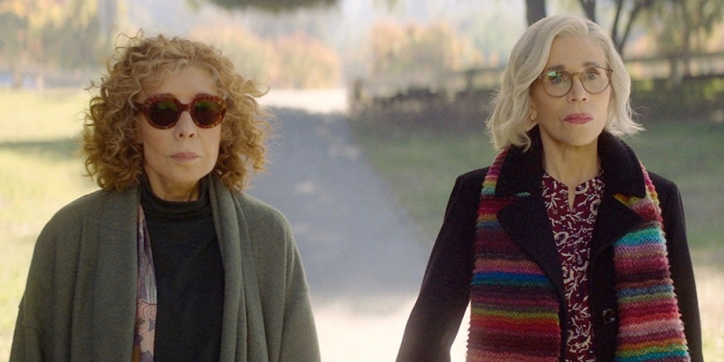 Lily Tomlin and Jane Fonda stand next to each other wearing sweaters.