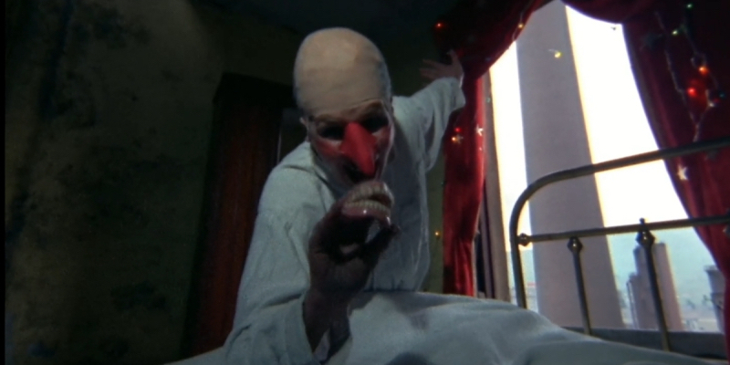 A figure with a long red nose, bald head, and scary makeup holds dentures in The Other Side of the Underneath.