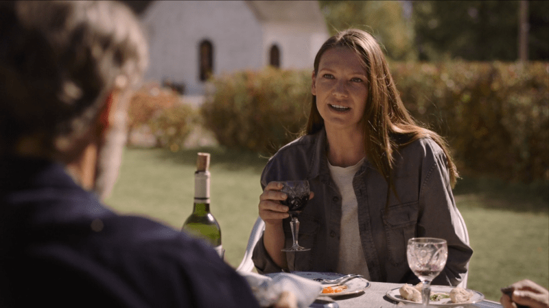 The Last of Us: 2010 Tess sits outside at a table and smiles at Frank during their garden party