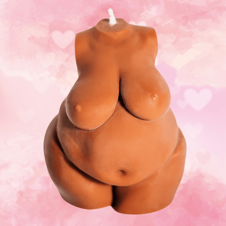 Against a white and pink background covered in hearts, there is a terracotta-colored candle shaped like the torso of a fat person with a round belly, curvy thighs, and large breasts.