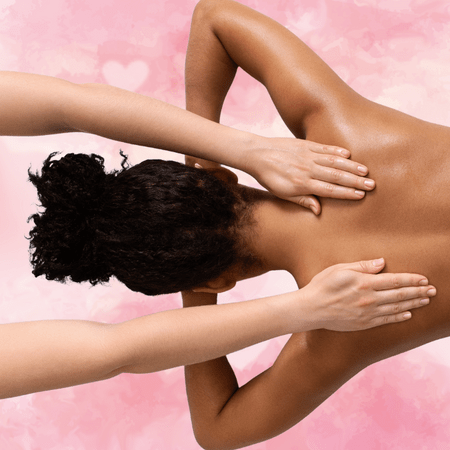 Against a white and pink background covered in hearts, a Black woman with her hair up lies on her stomach her elbows bent and her face against her hands. She is shirtless. The hands of a white woman extend from the left side of the image and massage the Black woman's back.