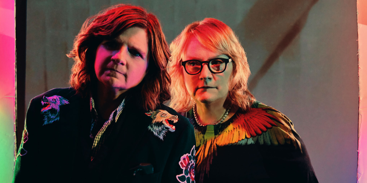 It's Only Life After All: Amy Ray and Emily Saliers in black jackets looking off in multicolored lights.
