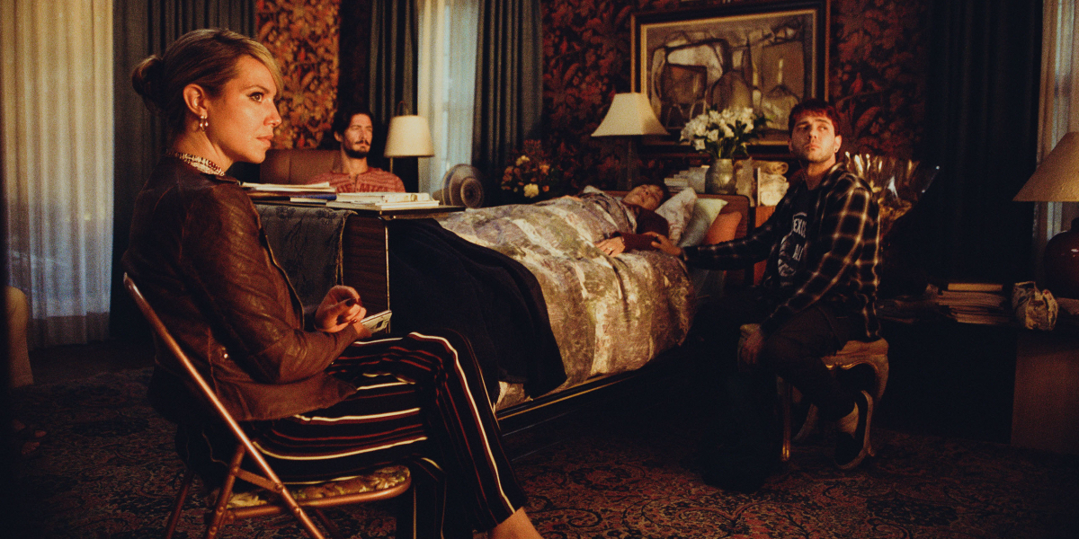 Magalie Lépine Blondeau, Éric Bruneau, and Xavier Dolan look up at a golden light as they sit around the deathbed of an older woman.