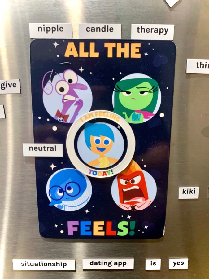 A collection of magnets from the movie "Inside Out" and the Autostraddle Word Magnet kit, on a grey refrigerator