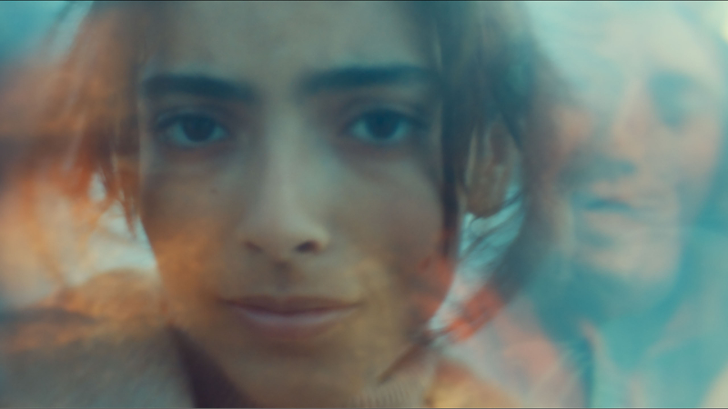 A close up of Oumaïma Barid as she looks into the camera. The image is distorted with another face emerging off to the side.