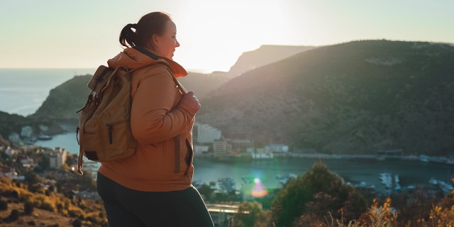 A woman with a backpack on a mountain, hiking away.