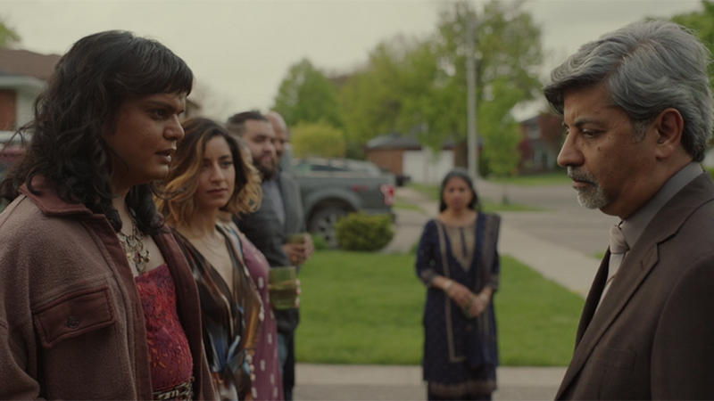 The Mehboob family stands in a line on the lawn to greet Imran. In the foreground, Sabi looks at their father, who can't return Sabi's gaze. Just behind Sabi is their sister Aqsa and in the distance we see their mother Raffo. 