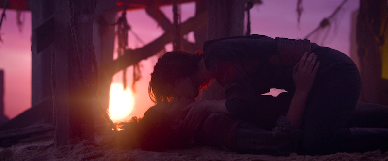 Kit kissing Jade in front of beautiful purple, blue, and pink lighting