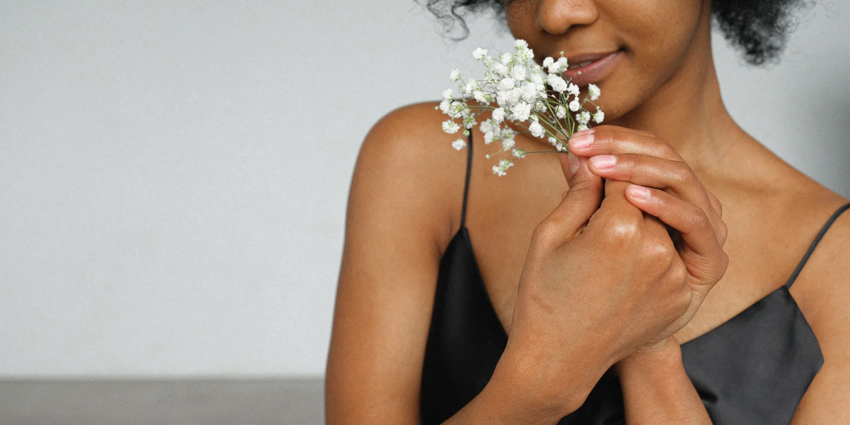 Black person holding baby's breath wearing a Black slip dress