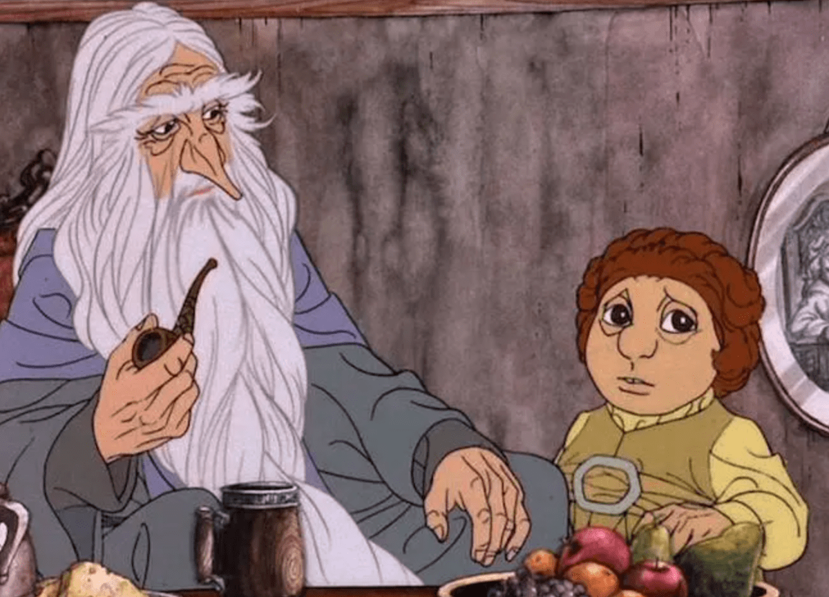 a still from the rankin bass animated hobbit with gandalf and bilbo sitting at table. gandalf has no hat and is holding a pipe