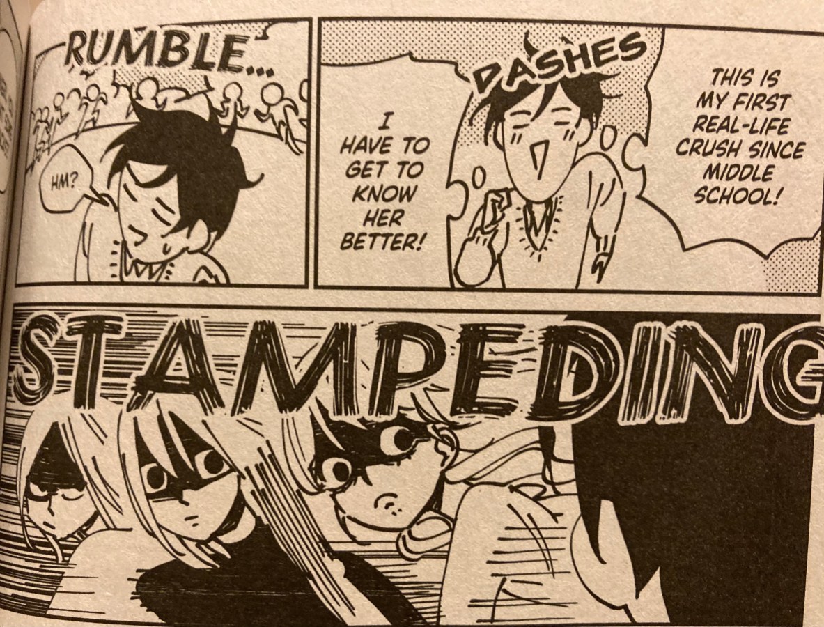 Picture of a page from the book. In the first panel, Mieri is rushing towards her crush saying "This is my first real-life crush since middle school! I have to get to know her better!". In the second panel, Mieri hears a rumble of people in the distance behind her and says "Hm?" as she glances over her shoulder. In the third panel, three feminine girls stare at Mieri as they stampede past her at impossible speeds.