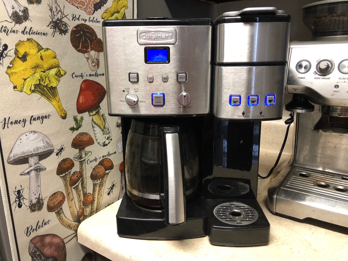 A programmable coffeemaker sits on a counter next to a mushroom tapestry