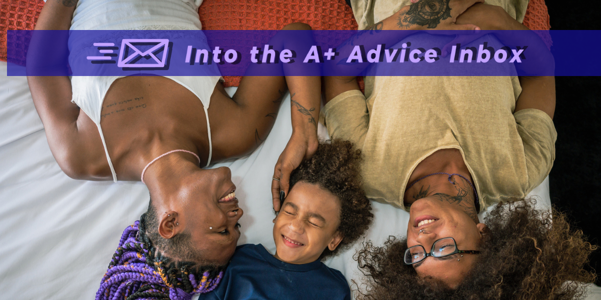 a Black queer couple smiles happily on a bed with their child. one member of the couple has hair in a purple protective style. the child and the other partner have their hair in a natural style. both parents have tattoos