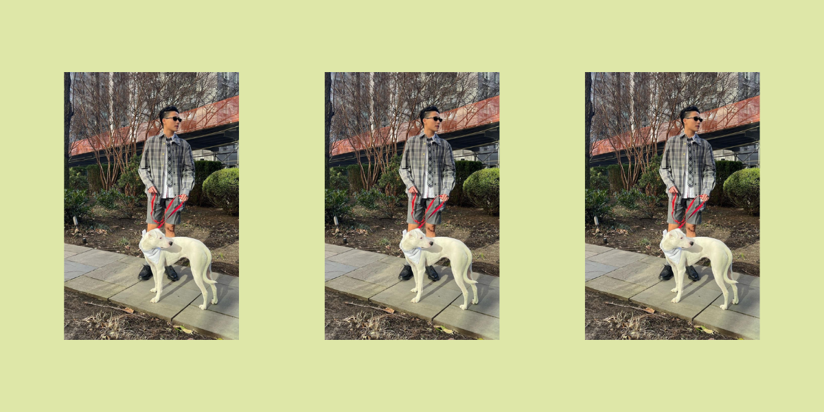 Melissa King in a plaid jacket and shorts walks a big white dog on a sidewalk