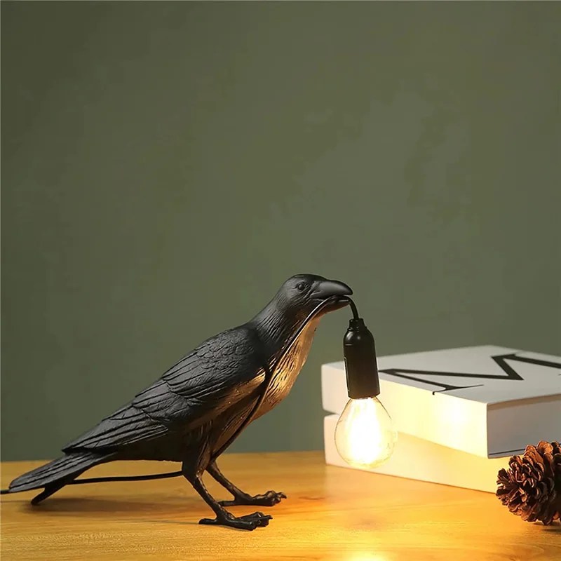 A raven figurine holds a light bulb in its mouth