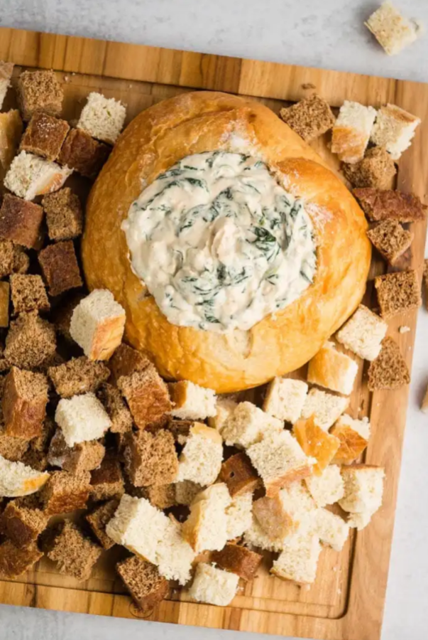 a bread bowl filled with spinach dip