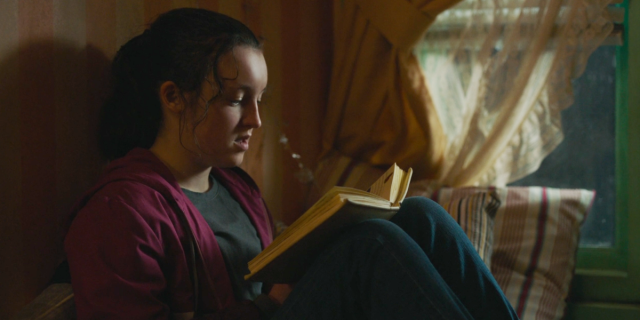 Screenshot from The Last of Us: Ellie sits on a window seat and reads a teen girl's diary