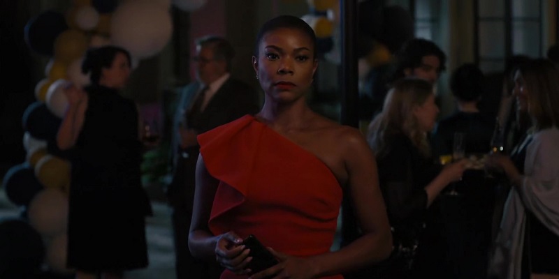 Truth Be Told: When Eva discovers that Finney purchased the gold chains, she stares at him with recognition. Gabrielle Union's Eva has her hair tightly pulled back into a bun. She's wearing a red one shoulder dress with ruffles on her right shoulder and left hip. She also has on matching red lipstick. She is carrying her phone. 