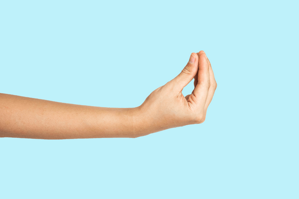 A white woman's arm extends from the left side of the image against a light blue background. Her fingers are pressed together in a fisting gesture.