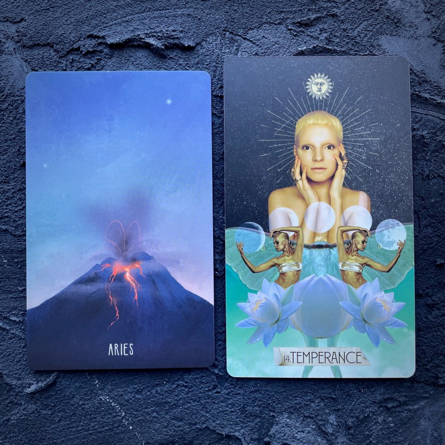 Two cards in front of a navy blue background, right to left: Aries (a volcano) and Temperance (a white person holding their face in their hands)