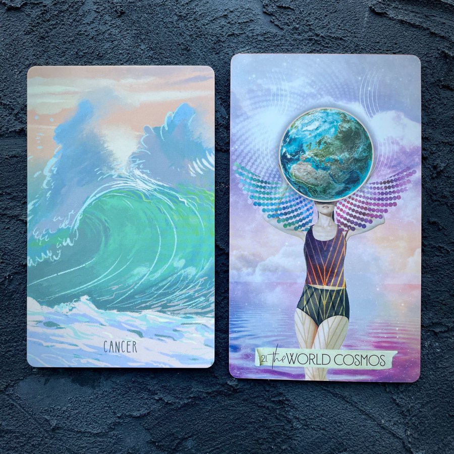 Two cards in front of a navy blue background, right to left: Cancer (a cresting ocean wave) and the world cosmos (a woman with winds and a globe over her face)