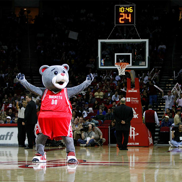 Clutch Bear in a red Rockets basketball uniform on a basketball court, holding his arms out in victory 
