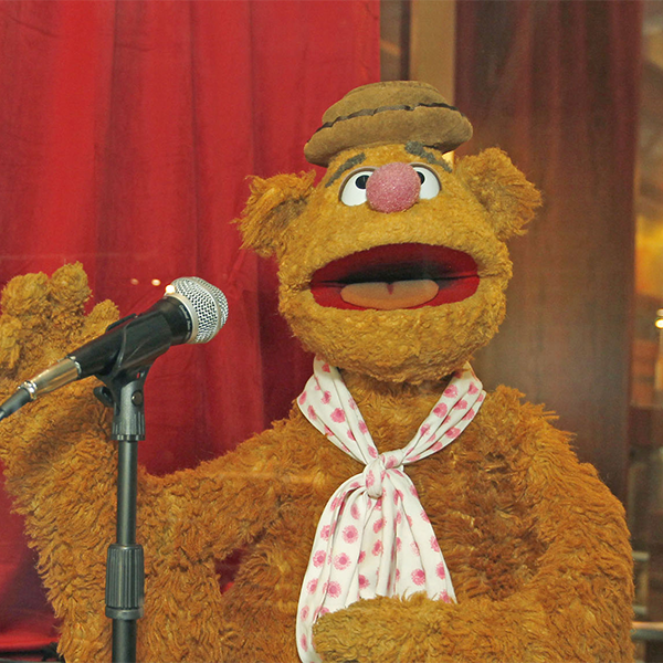 Fozzie Bear tells a joke at a microphone