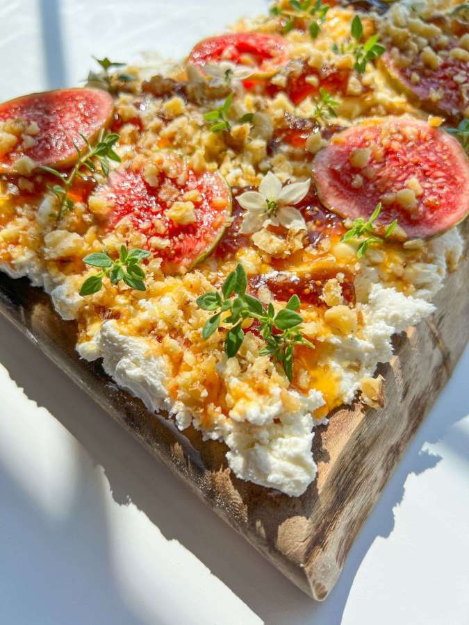 a spread of goat cheese with toppings on a board