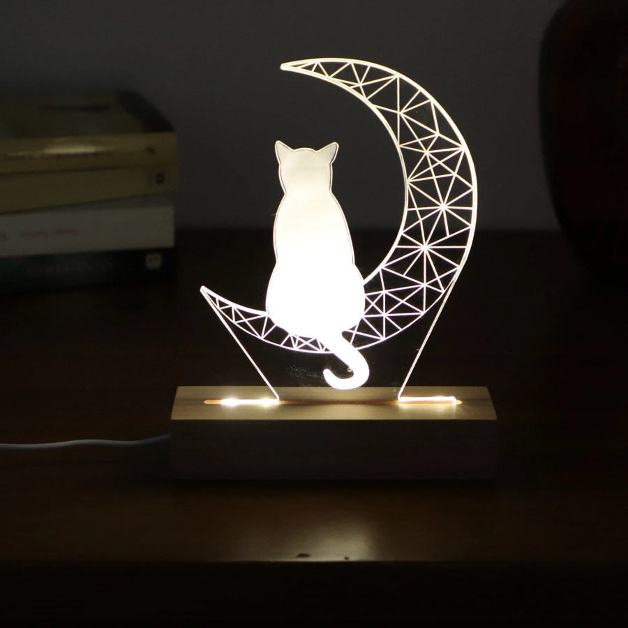 a cat on a crescent moon light on a bedside table