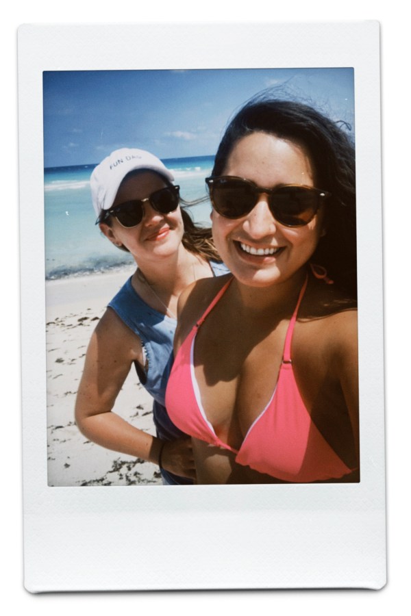 Kristen and Kayla on the beach, Kayla in a pink bikini and Kristen in a blue tank with white baseball cap