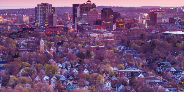 a cityscape of New Haven, CT at dusk, dappled in pink sunlight
