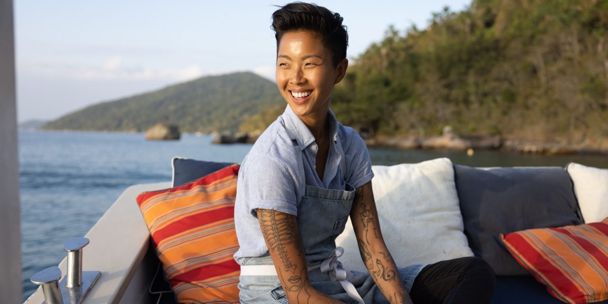 Korean-American chef Kristen Kish sitting on a boat and smiling