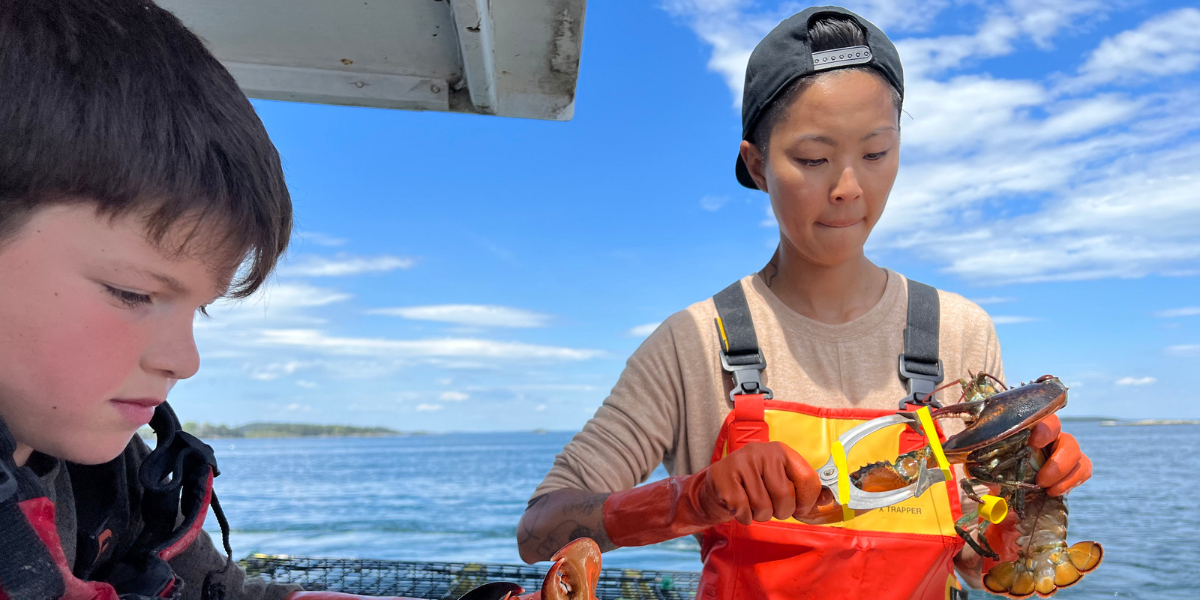Korean-American chef Kristin Kish holding a lobster while on a boat.