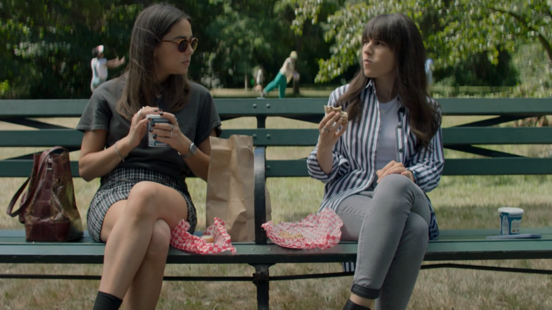 The Watchful Eye: Elena and Alex sit on a park bench and eat bagels and drink coffee while chatting