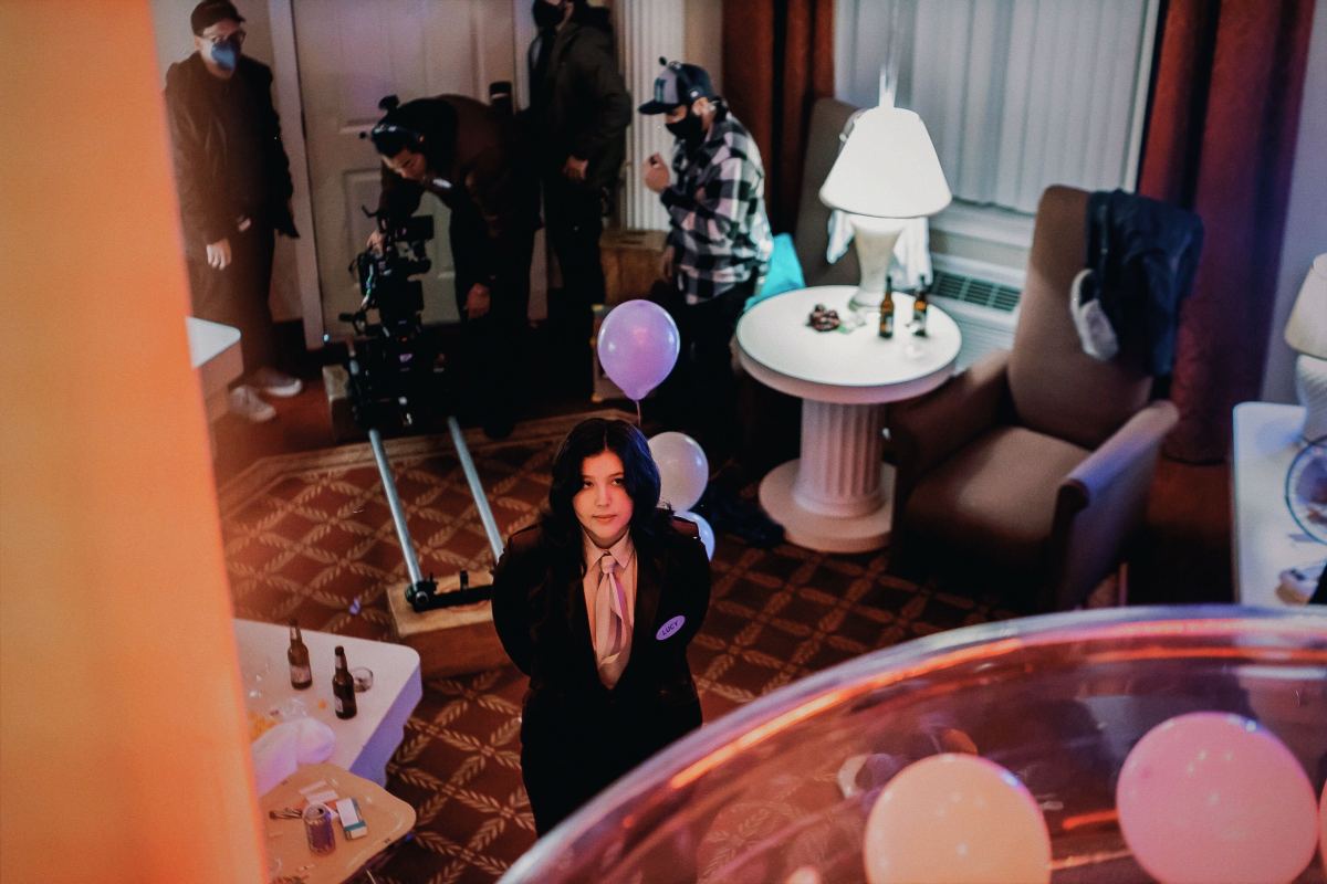 Lucy Dacus stands in a hotel while filming the "Night Shift" music video and is wearing a nametag that says LUCY on it