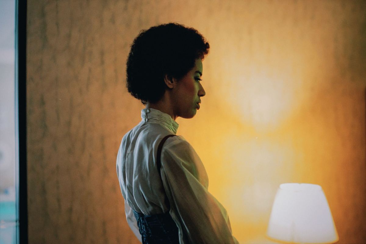 Jasmin Savoy Brown in the music video for "Night Shift" stands in a glowing hotel room