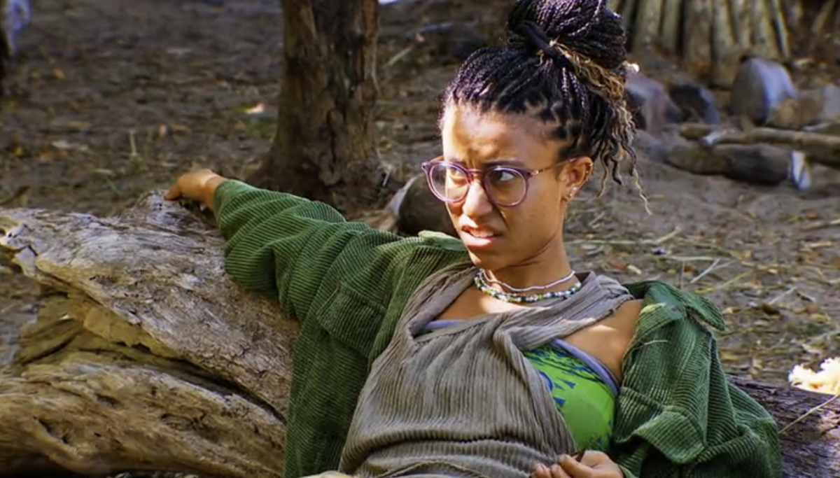 Survivor Season 44 contestant Claire Rafson reclines against a log, looking positively annoyed by whatever the people next to her (not pictured) just did